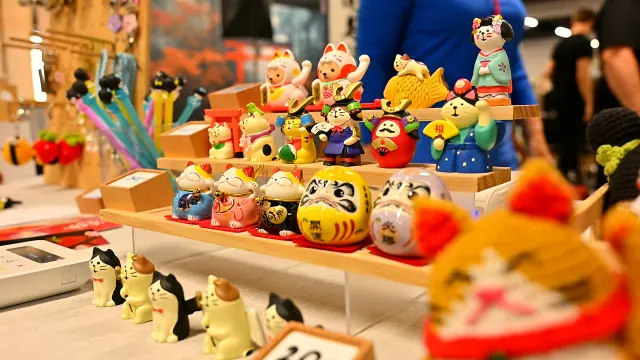 Szydełkowe maneki-neko i daruma na stoisku rękodzieła