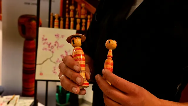 Drewniane laleczki kokeshi w dłoniach twórcy