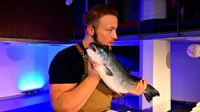 Kucharz prezentuje całego łososia na scenie