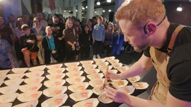 Kucharz nakłada sashimi na tacki, goście patrzą