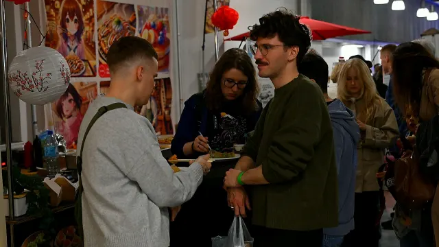 Goście jedzą w alejce między stoiskami