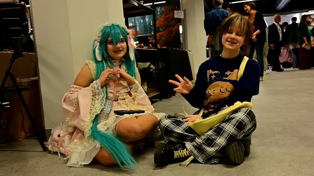 Cosplayerki siedzą na podłodze i machają
