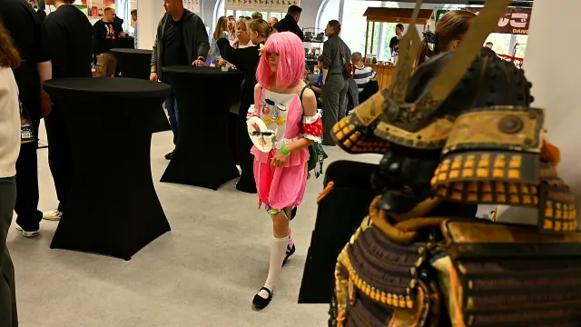 Cosplayerka i zbroja samurajska na pierwszym planie