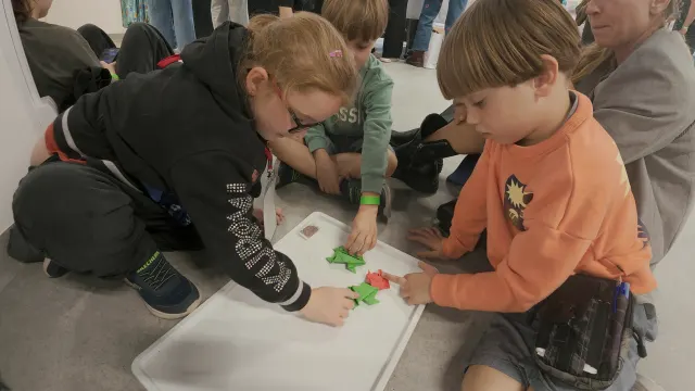 Dzieci składają origami na warsztatach
